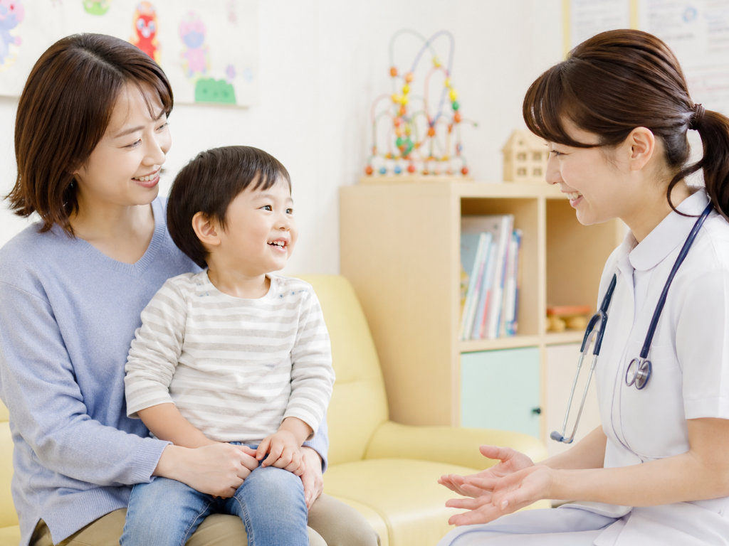 小児科で医師が保護者と子どもにやさしく説明している診察室の写真