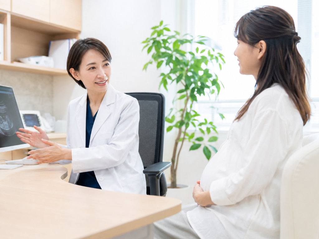 産婦人科で医師が妊婦さんに超音波画像を見せながら説明している写真
